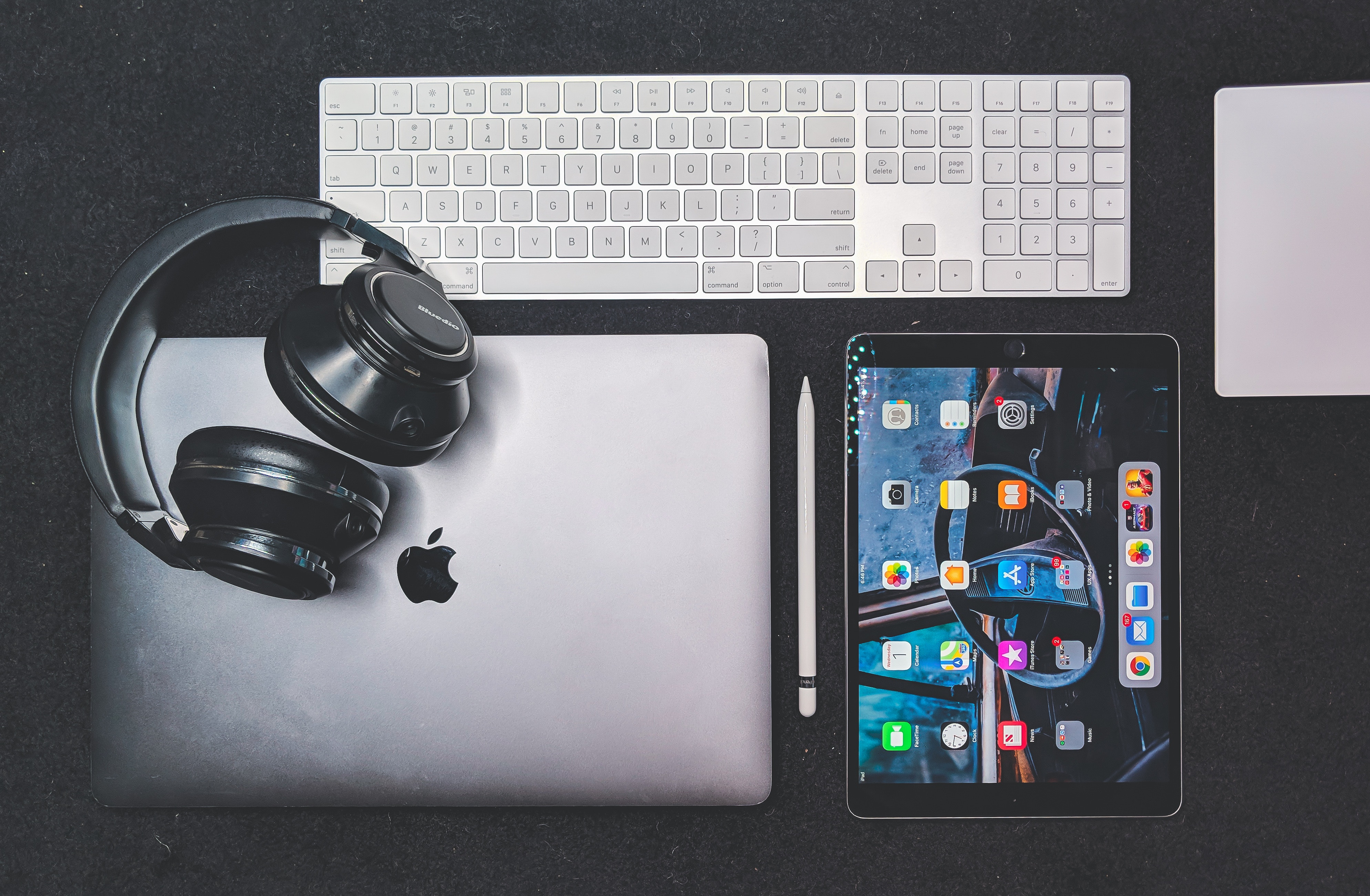 A collection of apple products, including a macbook pro, ipad, keyboard, headphones.